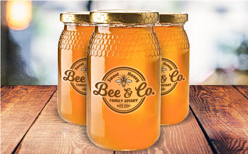 Clear labels with Bees Co. logo on three mason jars full of honey.